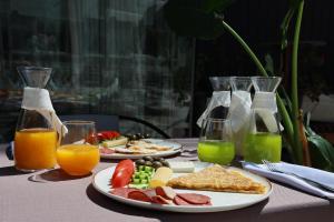a table with two plates of breakfast foods and orange juice at NOMA Boutique Hotel in Shkodër