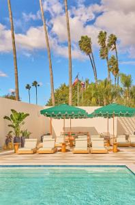 a pool with chairs and umbrellas next to a swimming pool at Cameo Beverly Hills, LXR Hotels & Resorts in Los Angeles