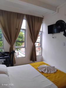 a bedroom with a bed and two windows at Hotel SR, Villa Garzón in Villagarzón