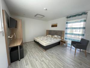 a bedroom with a bed and a chair and a television at Schäfer Apartments in Oberderdingen