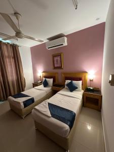 a hotel room with two beds and two tables at Savoy Inn Hotel Apartments in Muscat