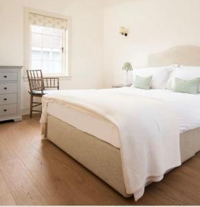 a white bedroom with a large bed and a chair at Hoolet's View, East Lothian in Whittingehame