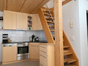 a kitchen with wooden cabinets and a spiral staircase at Penthouse duplex with sauna & mountain views in Pontresina