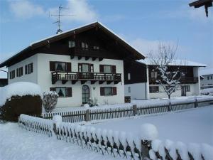 a snow covered house with a fence in front of it at Ferienwohnungen Wennesz in Chieming