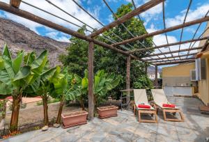 a patio with chairs and plants and a pergola at GC0284 El Granero in Mogán