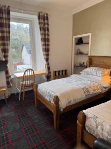 a bedroom with two beds and a desk and a window at Tanglin Guest House in Oban +53 photos
