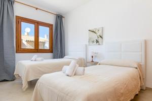 two beds in a white room with a window at YourHouse Casa Rafael in Can Picafort