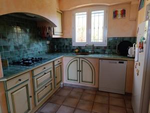 a kitchen with white cabinets and green tile walls at La bastide 4 chambres in Artignosc-sur-Verdon