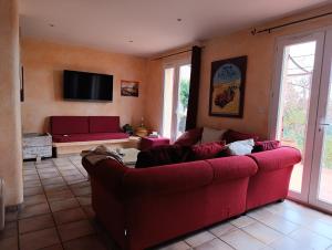 a living room with a red couch and a tv at La bastide 4 chambres in Artignosc-sur-Verdon