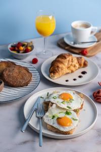 a table with plates of breakfast foods and a glass of orange juice at Hotel Kodawari Flores - by Kodawari Residences in Porto