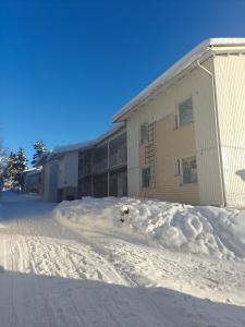 a snow covered street in front of a building at Luhtitalo two-room apartment in Rovaniemi