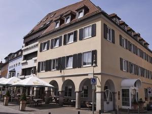 a large building with tables and umbrellas in front of it at DORMERO Hotel Crailsheim in Crailsheim