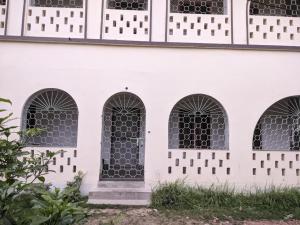 a white building with four windows and a door at Saraswati Kunj in mayapur