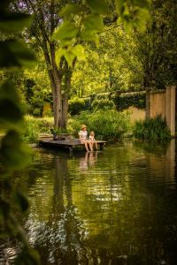 two children sitting on a dock in the water at The River Villa in Magaliesburg
