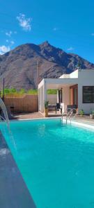 a swimming pool in front of a house with a mountain at Cabañas Torres del Sol in Vicuña