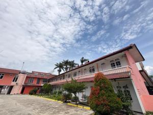a row of buildings with palm trees and a cloudy sky at Hotel Ompu Herti in Balige