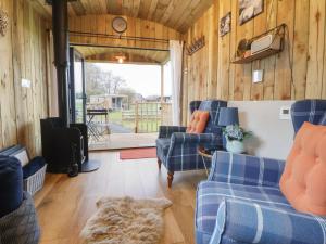 a living room with wooden walls and blue couches at The Suffolk Hut in Knutsford