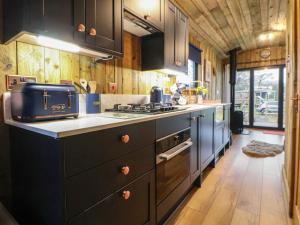 a kitchen with black cabinets and a counter top at The Suffolk Hut in Knutsford