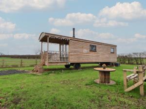 a tiny house on a truck in a field at The Suffolk Hut in Knutsford