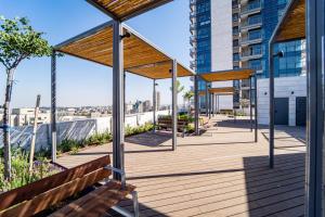 a wooden deck with a bench and a building at Savyon View Tower - Isrentals in Jerusalem