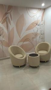 two chairs in a room with a flower wall at Backwoods inn in Heggadadevankote