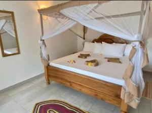 a bedroom with a bed with a canopy at TWIGA APARTHOTEL by Sofia Collection in Pwani Mchangani +14 photos