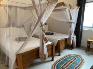 a bedroom with two beds with mosquito nets at TWIGA APARTHOTEL by Sofia Collection in Pwani Mchangani
