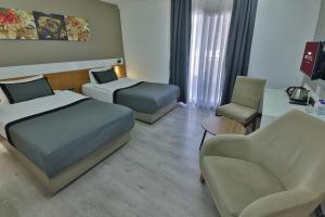 ein Hotelzimmer mit zwei Betten und einem Stuhl in der Unterkunft Buca Mat Hotel By Tahtalı in Izmir