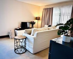 a living room with a white couch and a table at Klein Geluk Cottage in Stellenbosch