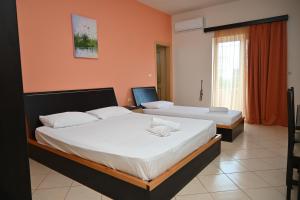 two beds in a room with orange walls at Ksamil Harmony Studios in Ksamil
