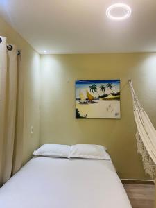 a bedroom with a white bed with a painting on the wall at Casa em Praia de Flecheiras in Trairi +37 photos