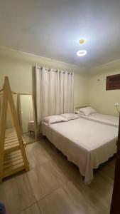 a bedroom with a large white bed and a window at Casa em Praia de Flecheiras in Trairi