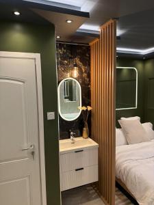 a bedroom with a bed and a sink and a mirror at Onyx Suite Jacuzzi Privatif in Villejust
