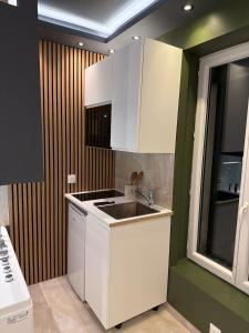 a kitchen with white cabinets and a sink at Onyx Suite Jacuzzi Privatif in Villejust