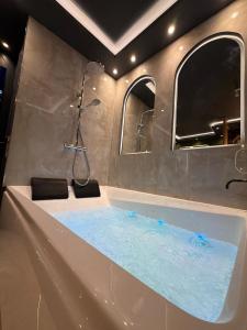 a bathroom with a tub with blue water in it at Onyx Suite Jacuzzi Privatif in Villejust