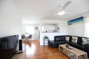 a living room with a black couch and a table at Enchanted Garden, 3 bedrooms in Sandstone Point