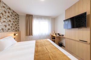 a hotel room with a bed and a flat screen tv at The Originals City Hôtel-Restaurant-Terrasse du PAarc Gravelines Dunkerque in Gravelines