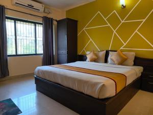a bedroom with a large bed with a yellow wall at Hill View Residency in Kalpetta