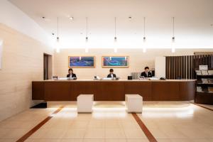 three people sitting at a desk in a waiting room at Hotel JAL City Miyazaki in Miyazaki