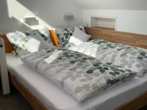 a bed with a gray comforter and pillows at Ferienhaus Uferweg in Otterndorf