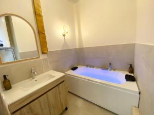 a bathroom with a tub and a sink and a mirror at Le Cocon du Büech in Veynes