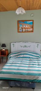 a bed with a blue and white striped comforter in a bedroom at La crapaudiere in Charrin