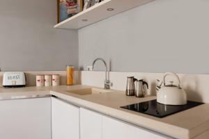 a white kitchen with a sink and a tea kettle at Campo de Fiori Bright Apartment in Rome