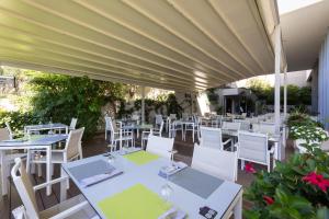 a restaurant with white tables and white chairs at Hotel Salona Palace in Solin