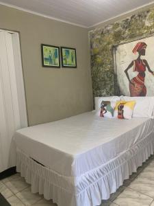 a bed in a bedroom with a painting on the wall at Suite Africana Aracaju in Aracaju