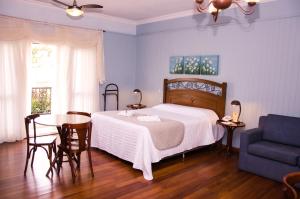 a bedroom with a bed and a table and a chair at Hotel Villa Michelon in Bento Gonçalves