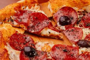 a pizza with pepperoni and olives on a wooden cutting board at Hotel Villa Michelon in Bento Gonçalves +89 photos