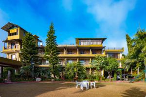 a building with two white chairs in front of it at Flying Sparrow Riverside Resort in Dhikuli