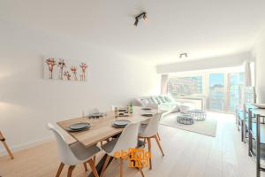 a white living room with a wooden table and chairs at Velasquez 0303 in Nieuwpoort