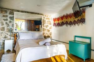 a bedroom with a bed and a stone wall at Casas D'Água Doce - Casa Amora in Ilhabela +68 photos